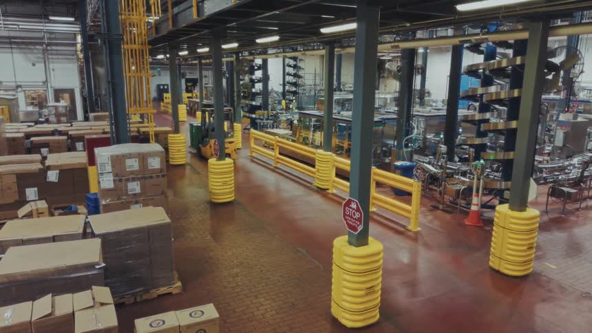 A person drives a forklift inside a warehouse filled with shipping boxes
