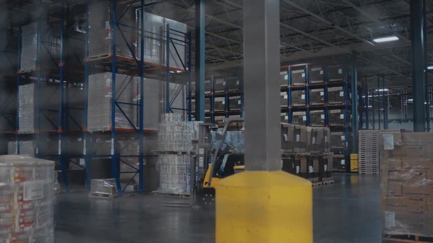 The man turns the forklift in the warehouse