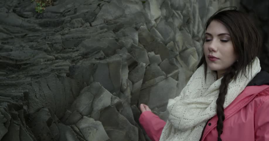 A woman wearing a pink coat walks along a canyon