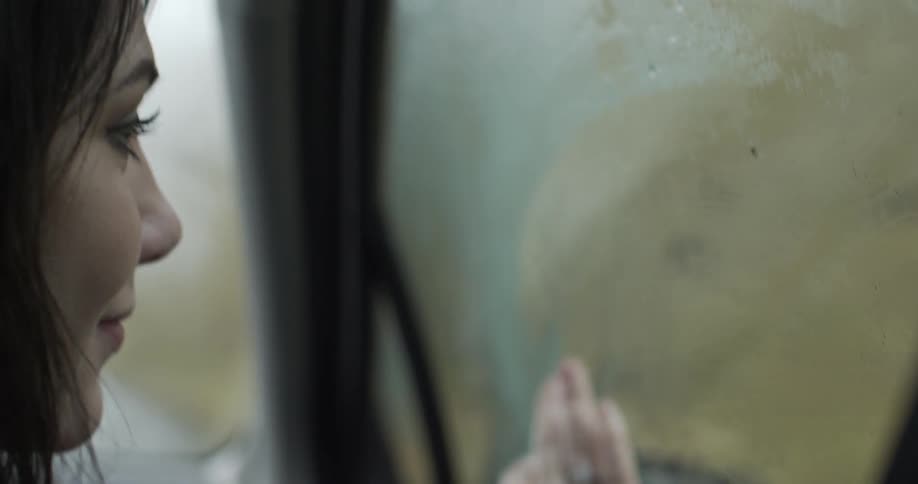 A woman wipes the moisture from a car window