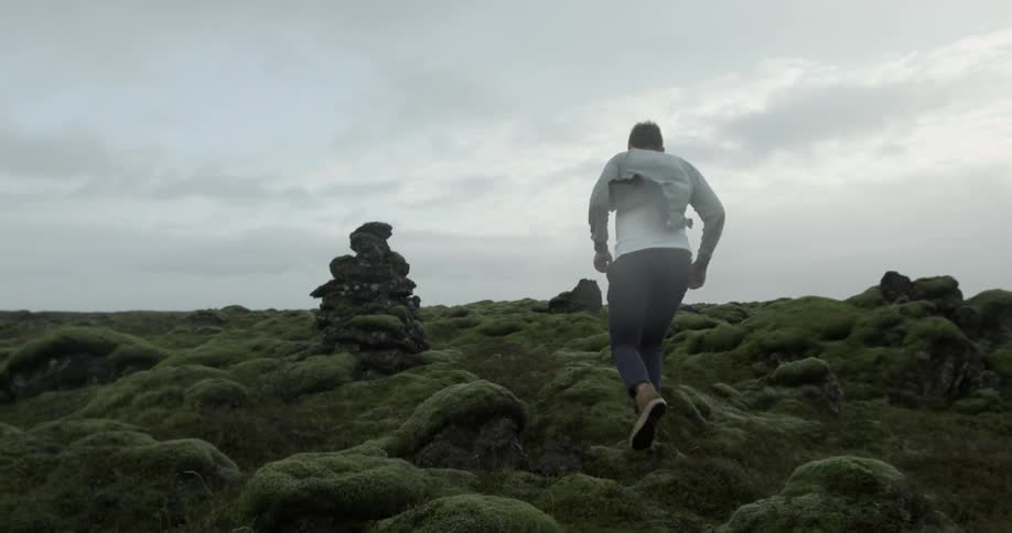 A man smiling and running on rocky ground