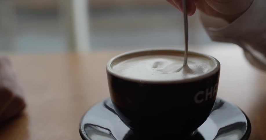 A person puts a cube of sugar in their drink