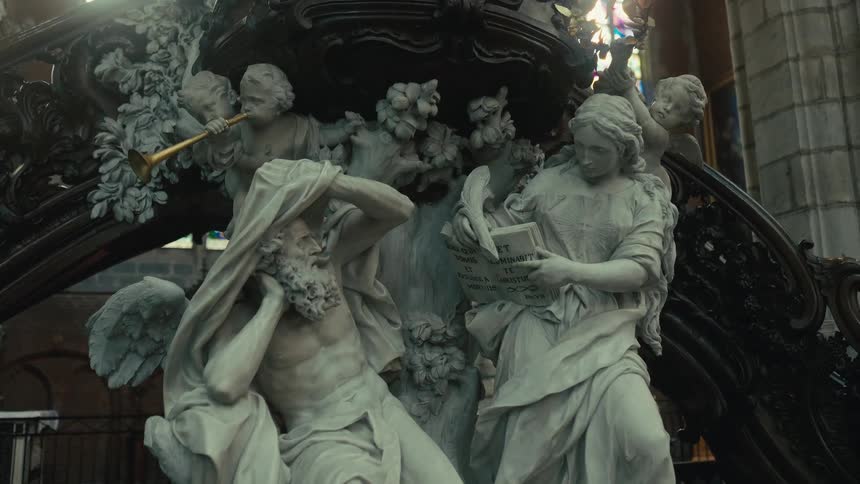 The video features an ornate dark wood or bronze structure likely a pulpit or a monumental architectural element adorned with highly detailed white marble or plaster sculptures in the foreground two main figures are depicted an older man with a long