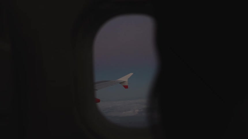 Silhouette of a woman closing an airplane window in midflight