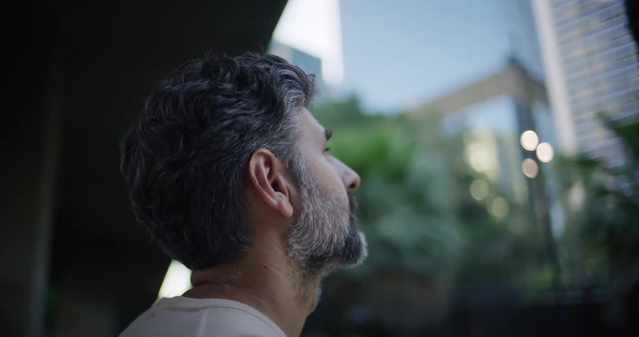 A man looking out a window at a city