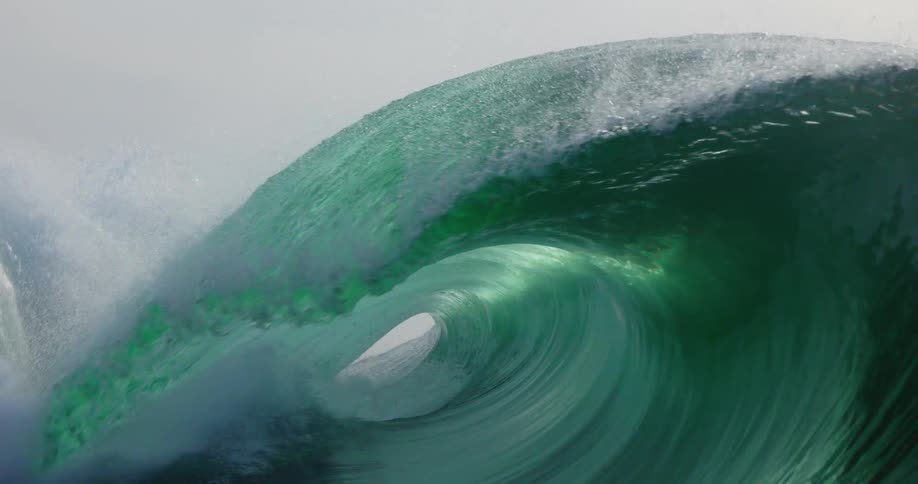 Wave splashes and curls as it rolls in toward shore