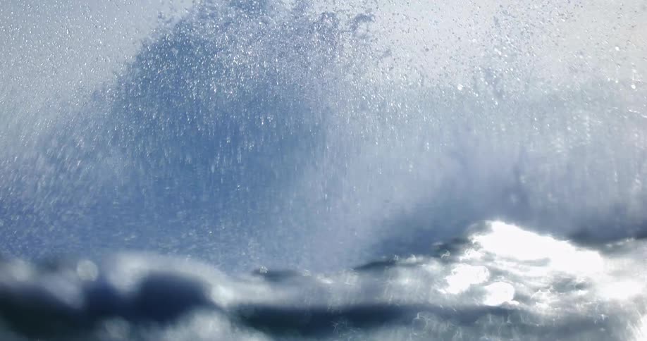 Sunlight shines on a wave splashing as it rolls in to shore