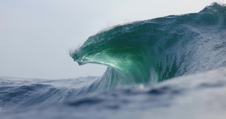Wave splashes and curls and the view moves partially underwater