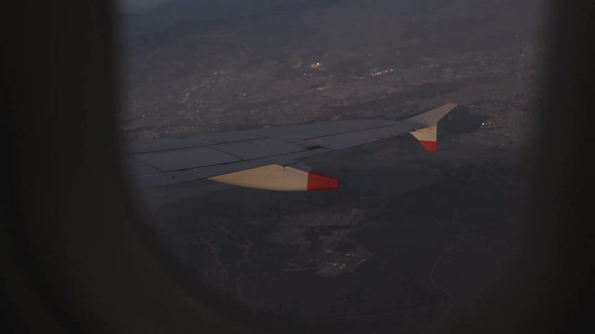 An airplane wing seen through the window midflight at sunset