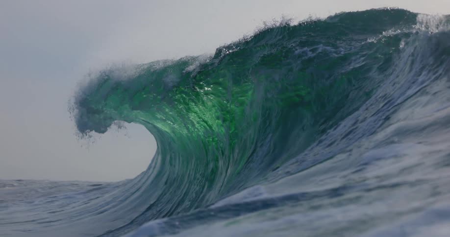 Wave curls and splashes as it rolls in toward shore