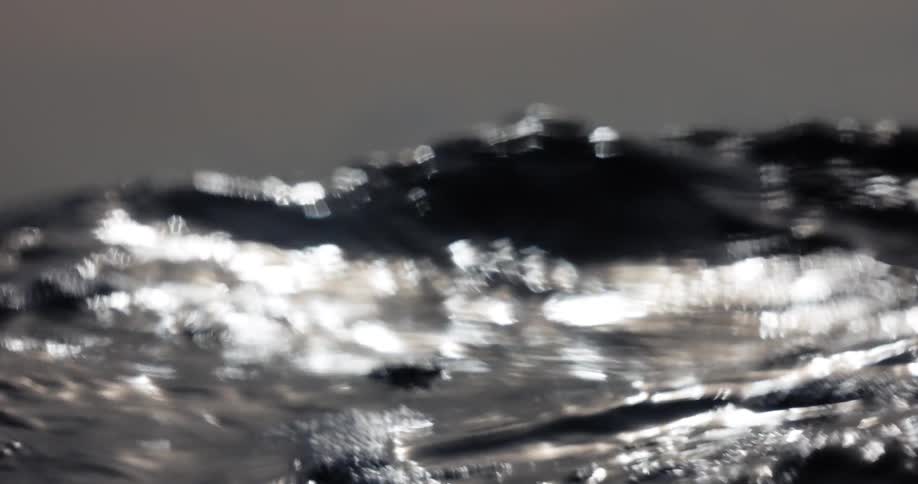 Liquid surface in motion with blurred light reflections in dark tones