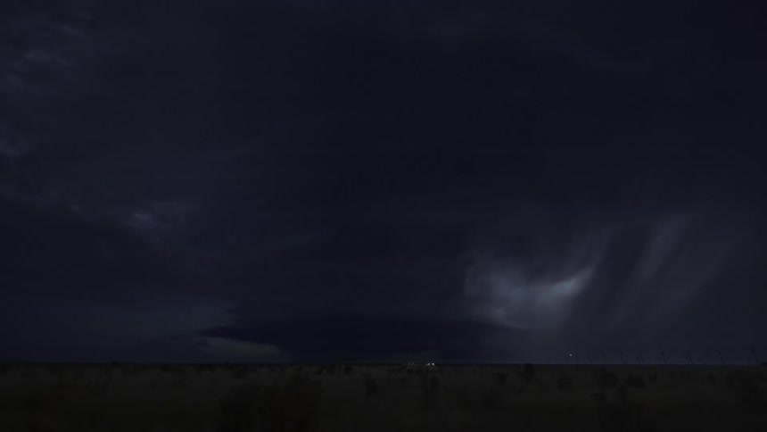 Lightning flashes and illuminates the sky as a super cell storm moves over rural land