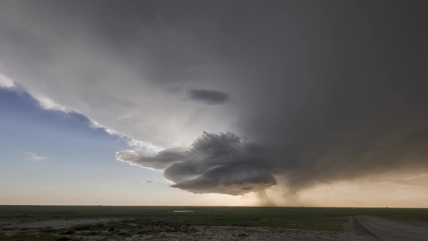 Super cell storm moves across the sky pouring rain over rural land