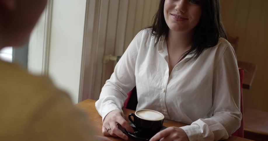 Man and woman sit at a table with cups of coffee
