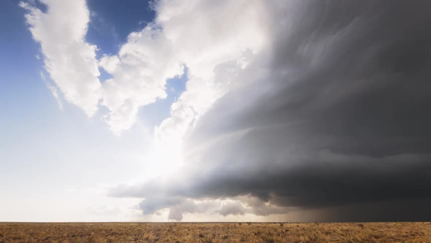 Super cell storm moves across the sky pouring rain over rural land