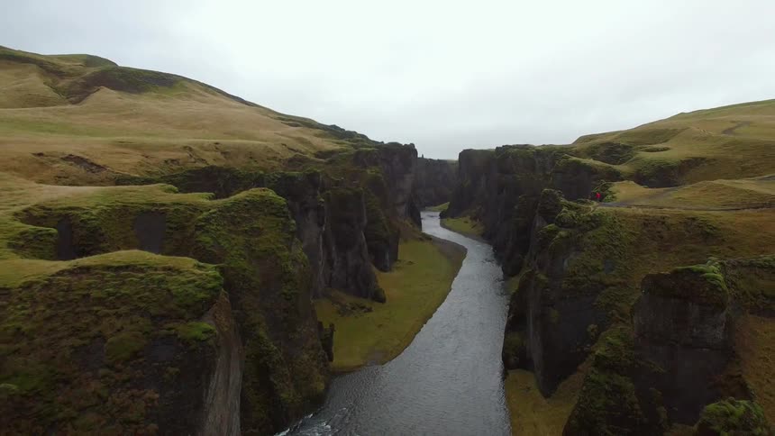 River running through large canyon of rock formations on overcast day