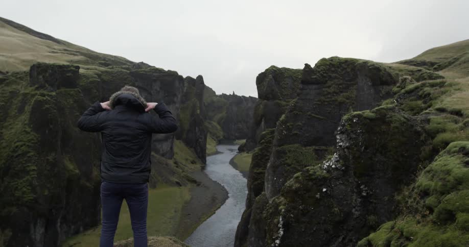 A person looks over a stream from a cliff