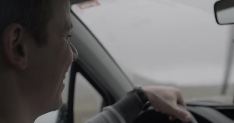 A man looks around smiling as he drives