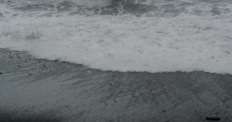 Ocean waves crashing onto beach on foggy evening