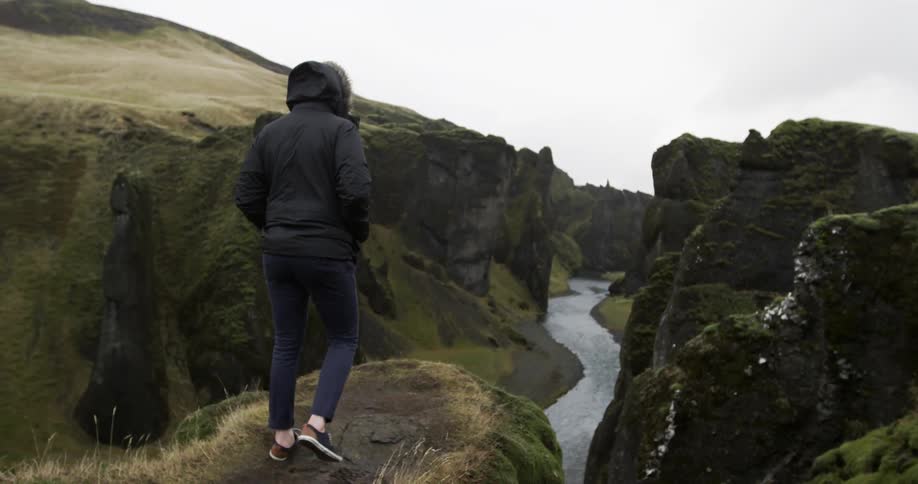 A person walks on a cliff over the water