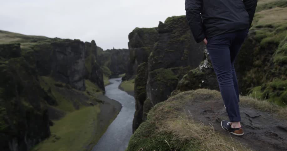 A person walks to the edge of a cliff