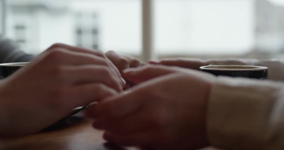 A person mixes their mug and holds hands with someone