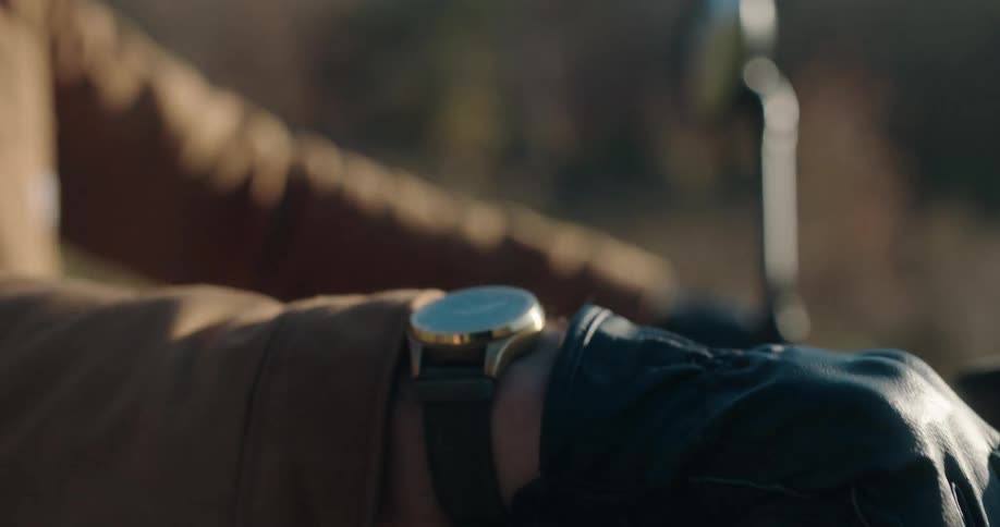 Hands wearing gloves while riding a motorcycle and a watch on the wrist