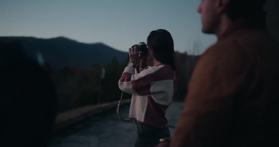 Woman using a professional camera in a mountainous environment next to a man