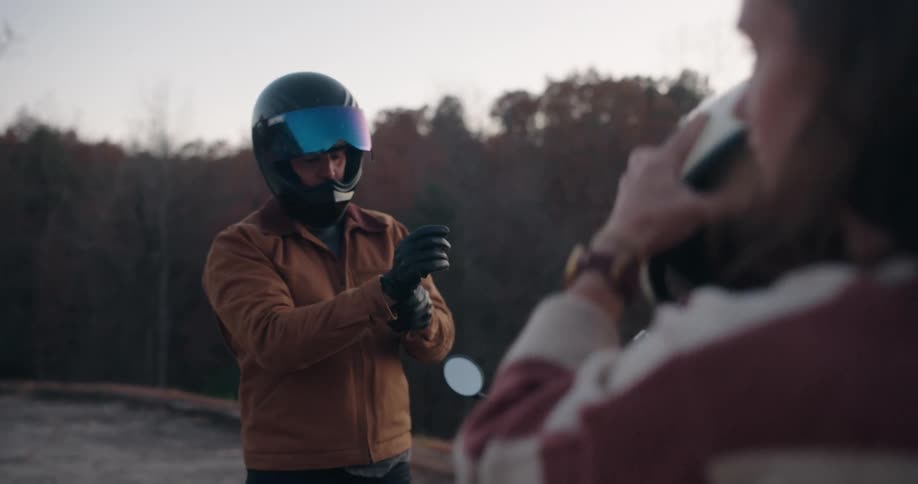 A man and woman getting off of a motorcycle