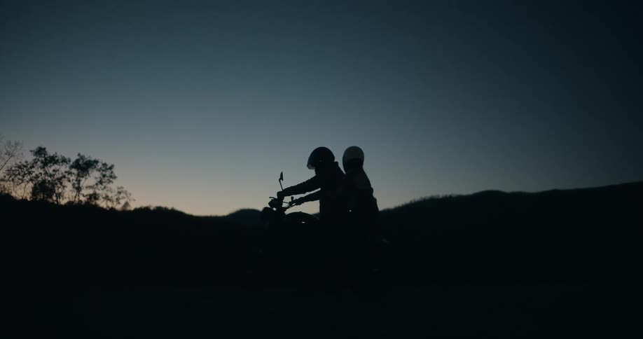 Two people getting onto a motorcycle