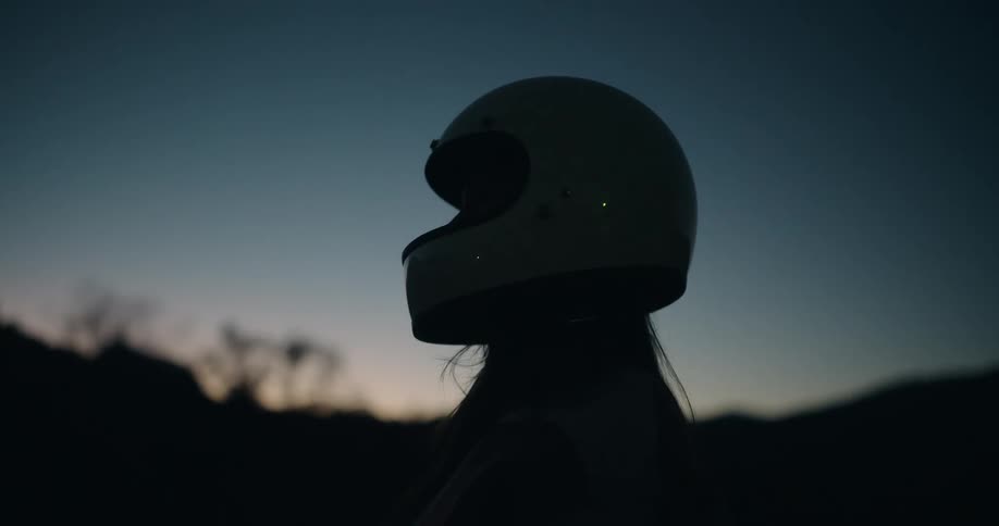 Silhouette of a woman putting on a helmet