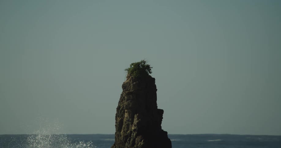Wave crashing against a natural rocky pillar