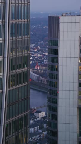 Two skyscrapers stand side by side in the city at sunset with the skyline visible beyond the buildings