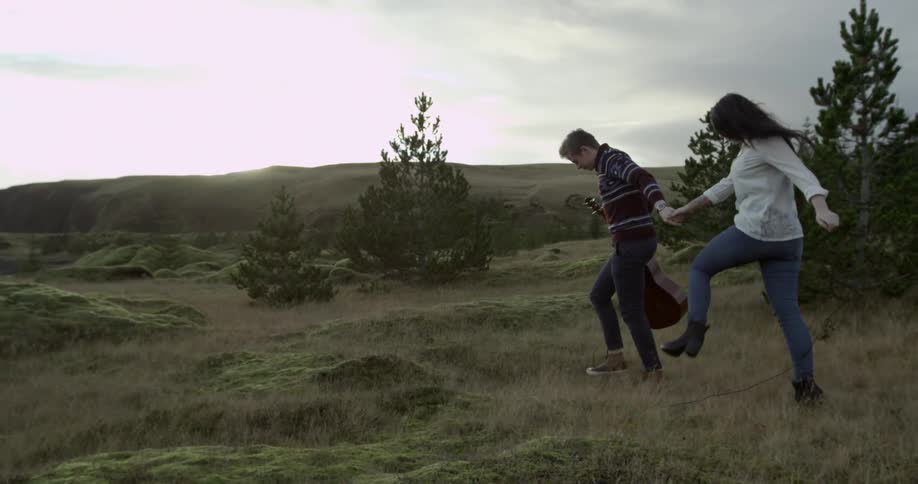 A man with a guitar leads a woman forward