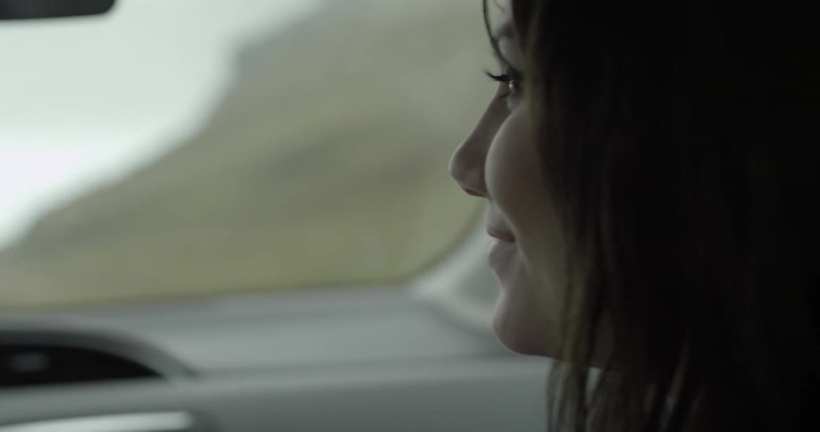 A woman smiles while in a moving car