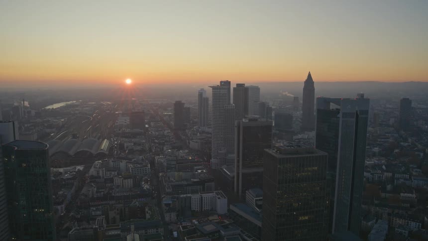 Aerial view of a city skyline at dawn with the sun rising over the horizon