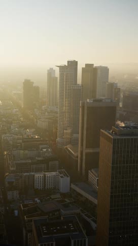 A city skyline at sunset with a foggy atmosphere on the horizon lined with highrise buildings and skyscrapers