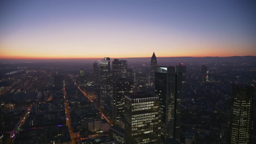Sunlight tints the horizon red as building lights shine from downtown buildings at night