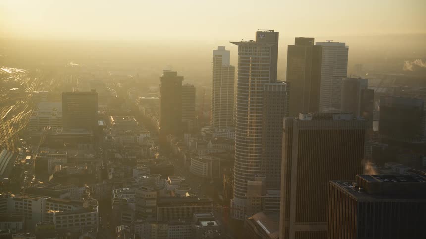 Aerial view of a dense metropolitan skyline bathed in the hazy golden light of sunset