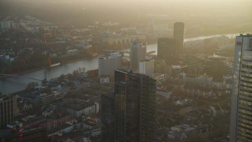 Sun shines from near the horizon onto a foggy river city