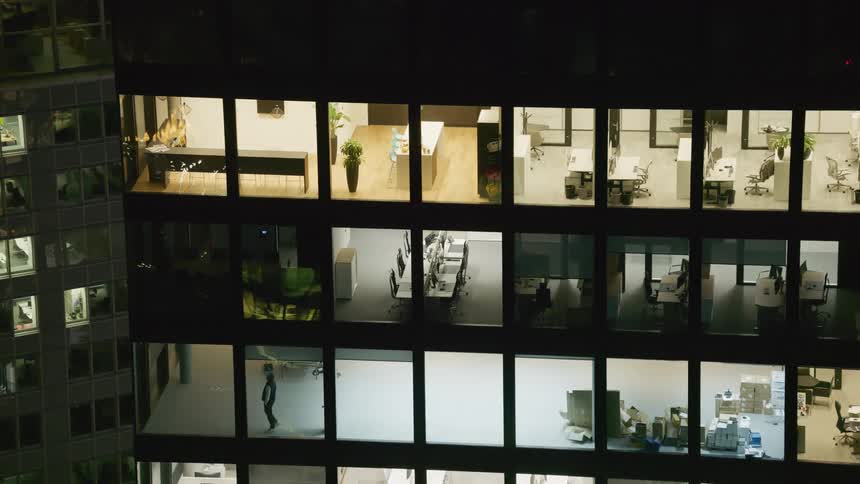 Office building with a view inside each unit with lights on and no curtains at night