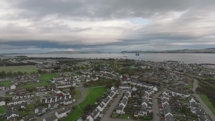 Aerial view of a coastal suburb with houses along the water under a cloudy sky