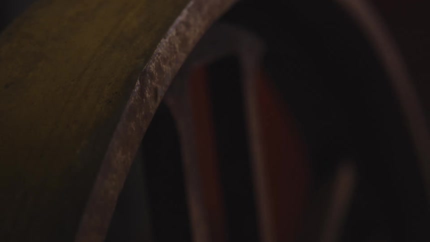 A series of closeup shots focusing on a large weathered wooden wheel possibly from a wagon or vintage machinery thick coiled ropes are visible in the background suggesting a maritime or historical industrial setting