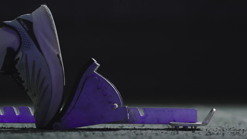 Starting block with a running shoe positioned for a track sprint start