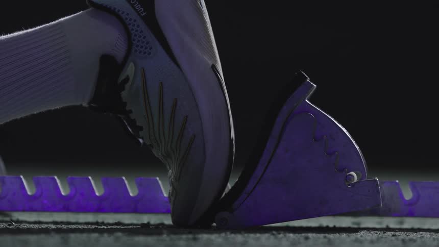 Feet with sneakers positioning themselves on a running starting tool