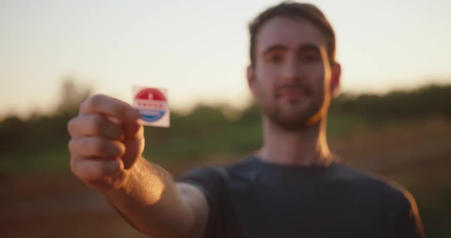 A man holds out his i voted today sticker for the camera to see
