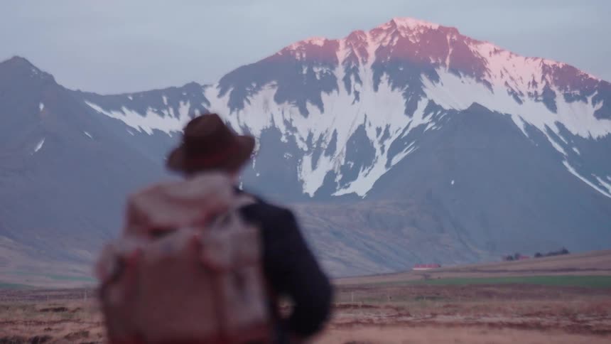 A person hiking toward some mountains covered in snow