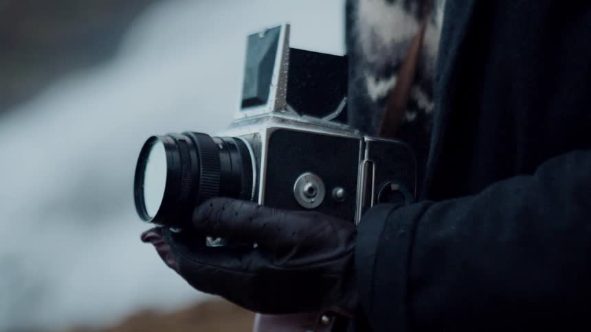 Analog camera is held by gloved hands in an outdoor environment