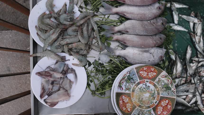 Close up of metal tray containing various plates of seafood and vegetables