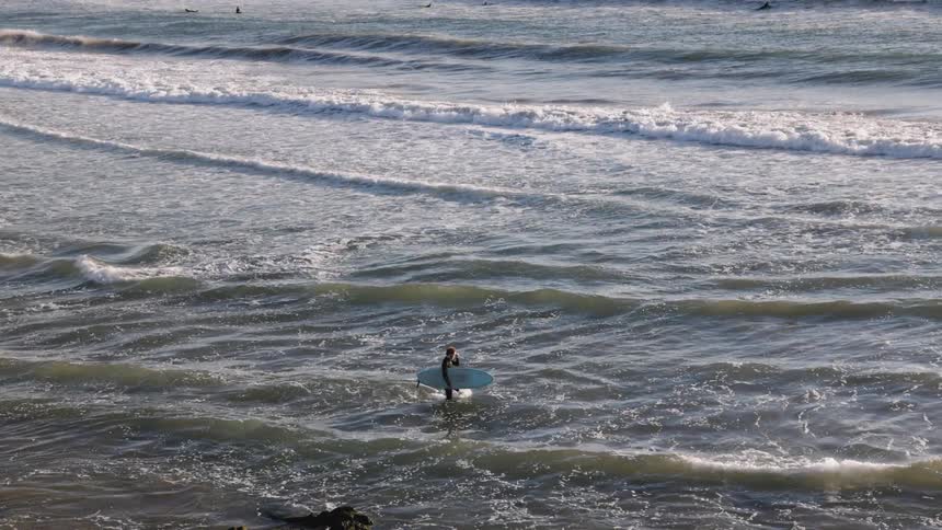 Surfer walking on the calm waves of the ocean